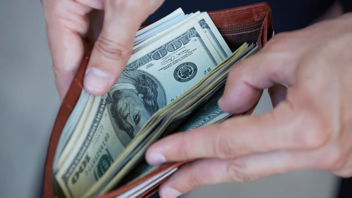 A close-up of a person opening a wallet with cash