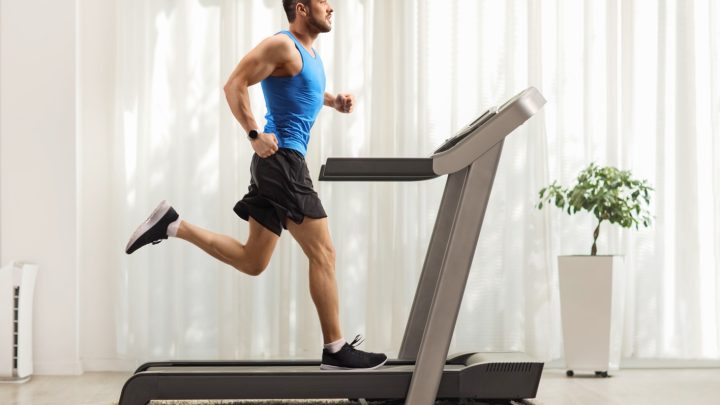 A young man running on a treadmill at home.