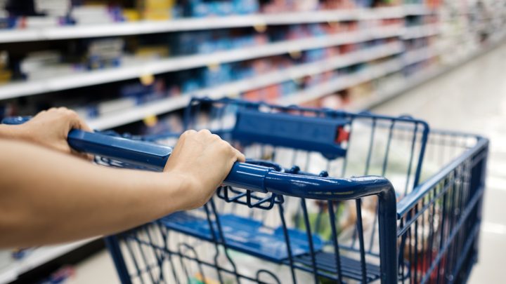 Closeup of shopper pushing a cart through a grocery aisle