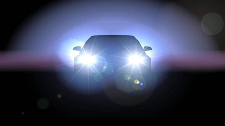 A car with bright headlights shining directly into the camera