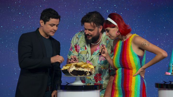 two men and one woman eat a cake