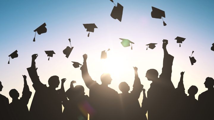 Silhouette of graduates throwing caps into the air