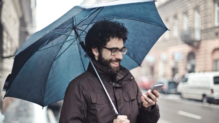man with umbrella holding phone