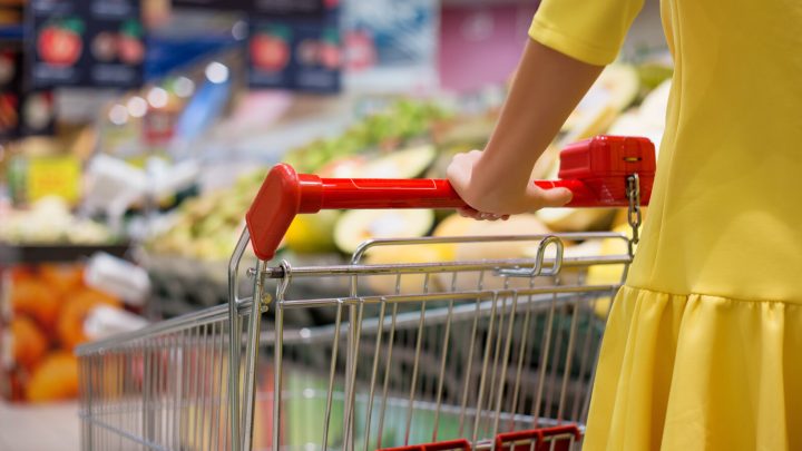 woman in yellow dress pushing grocery shopping cart
