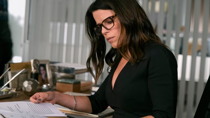 woman with dark hair and glasses working at a desk