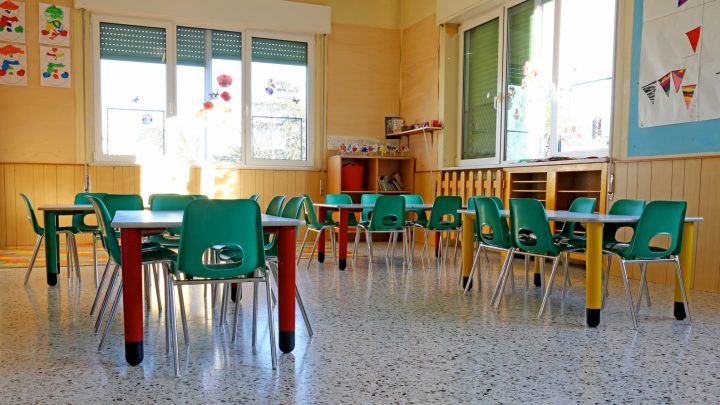 Interior of a kindergarten class with green chairs and children's decorations.
